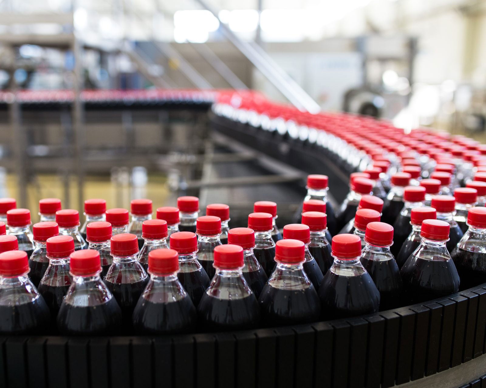 Capped soda bottles moving along a curved conveyor in a beverage bottling plant