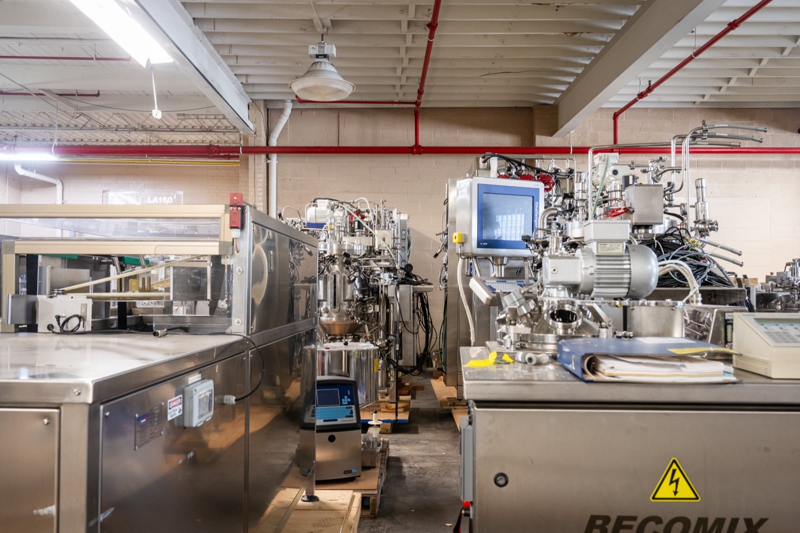 A Becomix mixer in the foreground, with stainless steel process and packaging equipment behind it, on the Federal Equipment Company warehouse floor in Cleveland, OH